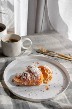 Beyaz tabakta pudra şekerli çıtır kruvasan. 