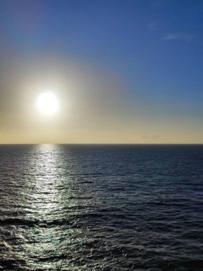 Güneş okyanusun üzerinde koyu mavi tonlarda batıyor.