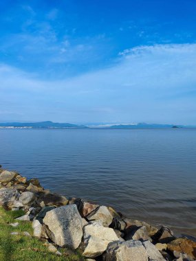 Sakin, sıcak bir yaz gününde, denizi çevreleyen kayalar.