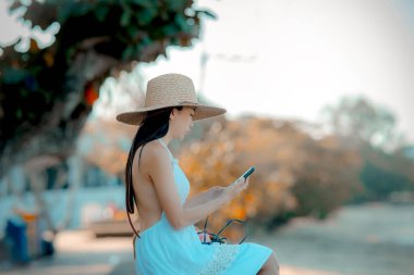 Kadın rahat bir şekilde oturur. Plajın kenarında rahatlar. Yaz tatilinde seyahat eder.