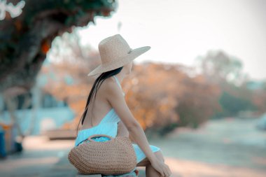 Kadın rahat bir şekilde oturur. Plajın kenarında rahatlar. Yaz tatilinde seyahat eder.