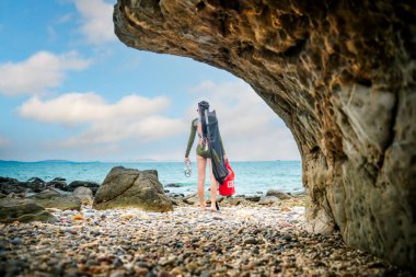 Dalış ekipmanları taşıyan kadın serbest dalış aktivitesi için denizin kenarına adım atıyor.