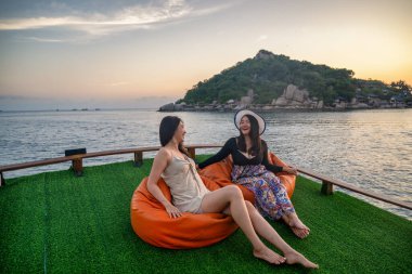 Elbiseli kadın, teknenin güvertesinde kal. Gün batımını izlemek için adaya yelken aç.