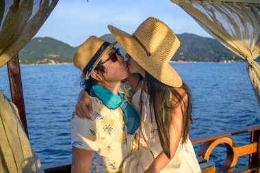 Romantik tatlı hareketler yapan bir çift yelkenliyle denizde gün batımını seyrediyor, yaz denizinde birlikte seyahat ediyor.