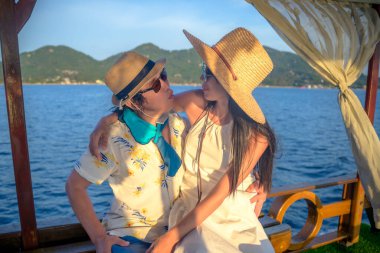 Romantik tatlı hareketler yapan bir çift yelkenliyle denizde gün batımını seyrediyor, yaz denizinde birlikte seyahat ediyor.