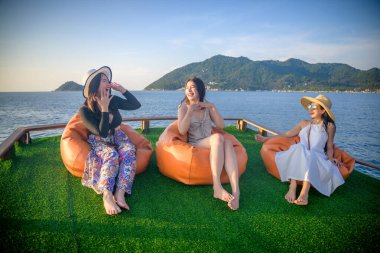 Bir grup turist yaz tatilinin tadını çıkarıyorlar. Birlikte tekneyle deniz kenarında akşam yemeği için seyahat ediyorlar.