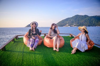 Bir grup turist yaz tatilinin tadını çıkarıyorlar. Birlikte tekneyle deniz kenarında akşam yemeği için seyahat ediyorlar.