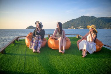 Bir grup turist yaz tatilinin tadını çıkarıyorlar. Birlikte tekneyle deniz kenarında akşam yemeği için seyahat ediyorlar.