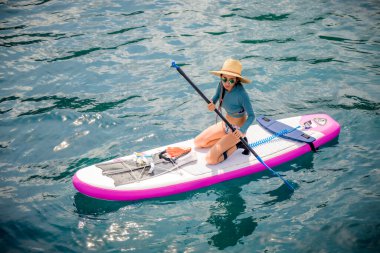 Denizde kürek çeken bir kadın. Yaz tatili. Hafta sonu adaya seyahat.