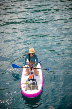 Denizde kürek çeken bir kadın. Yaz tatili. Hafta sonu adaya seyahat.