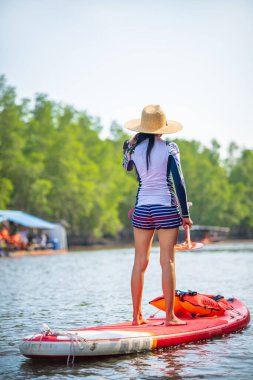 Kadınlar yağmur ormanlarının doğal göl nehrinde ayakta kürek çekmeyi severler.