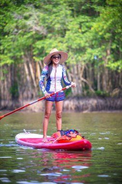  Turistler, yağmur ormanlarının doğal göl nehrinde stand-up sörfünün keyfini çıkarıyorlar.