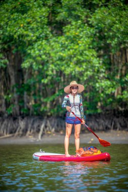 Kadınlar yağmur ormanlarının doğal göl nehrinde ayakta kürek çekmeyi severler.
