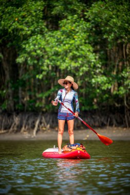 Kadınlar yağmur ormanlarının doğal göl nehrinde ayakta kürek çekmeyi severler.