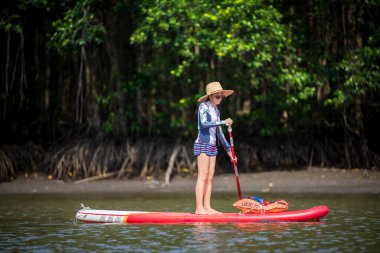 Kadınlar yağmur ormanlarının doğal göl nehrinde ayakta kürek çekmeyi severler.