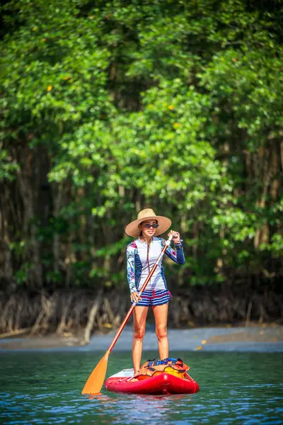 Kadınlar yağmur ormanlarının doğal göl nehrinde ayakta kürek çekmeyi severler.