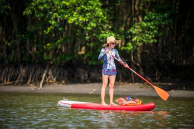Kadınlar yağmur ormanlarının doğal göl nehrinde ayakta kürek çekmeyi severler.