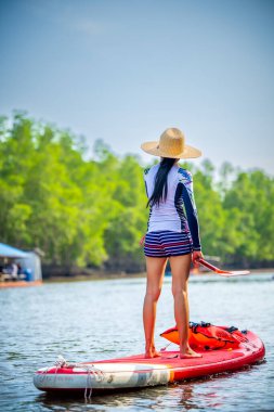 Kadınlar yağmur ormanlarının doğal göl nehrinde ayakta kürek çekmeyi severler.