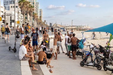 Tel Aviv, İsrail - 20.07.2022, Tel Aviv, İsrail - 20 Mart 2022, gün batımında plajda dinlenen kadın ve erkekler grubu