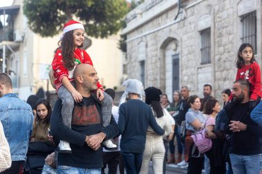 Hayfa, İsrail - 17 Aralık 2022: St. Elias Piskoposluk Okulu öğrencileri Alman Kolonisi 'ndeki Noel geçit törenine katıldılar. İzleyiciler geçidi izliyor