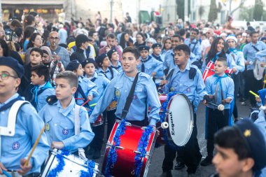 Hayfa, İsrail - 17 Aralık 2022: St. Elias Piskoposluk Okulu öğrencileri Alman Kolonisi 'ndeki Noel geçit törenine katıldılar. İzleyiciler geçidi izliyor