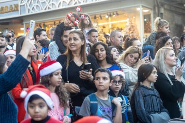 Hayfa, İsrail - 17 Aralık 2022: St. Elias Piskoposluk Okulu öğrencileri Alman Kolonisi 'ndeki Noel geçit törenine katıldılar. İzleyiciler geçidi izliyor