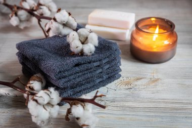 Dört gri Terry yüz havlusu, iki kalıp sabun, cam kavanozda bir mum ve kaplıcada bir dal pamuk. Güzellik salonu. Rahatlık ve bakım