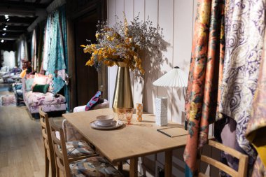 Yemek masasındaki bakır vazoda çimen olan uzun bir huş ağacı yaprağı buketi.