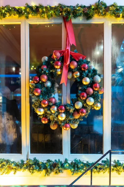 fir branch wreath in a minimalist style, decorated with a gold ribbon, decorates the green door before Christmas