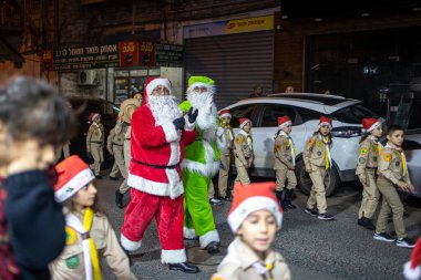 Haifa, Israel - December 17, 2022 : Pupils of St. Elias Episcopal school participate in the Christmas parade in the German Colony. Santa Clauses on stilts among scouts with drums.