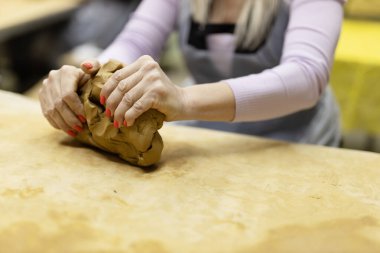 Female hands with red manicure crumple clay