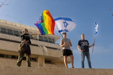 JERUSALEM, ISRAEL - February 20 2023: Israelis protest near the Knesset against plans by prime minister Benjamin Netanyahu. A girl with an LGBT flag, a young man with an Israeli flag clipart