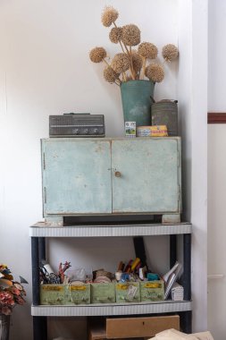 Dolapta kuru bir buket çiçek olan yeşil bir kova. Kutudaki aletler. Transistör radyo. Vintage mağazası