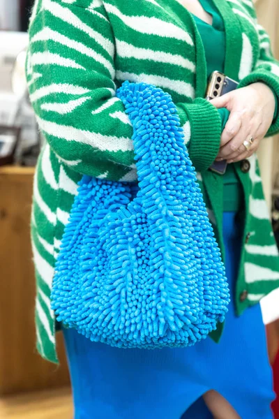 緑のニットのジャケットの女性は 彼女の手にフェイクファーで作られたニットブルーのホボショルダーバッグを保持しています — ストック写真