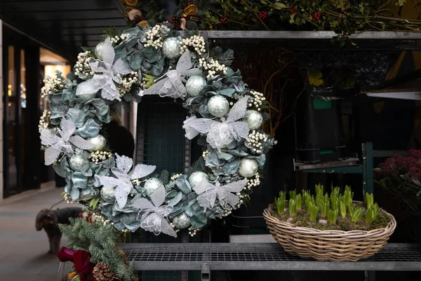 院子里装饰着一个圣诞花环 由人工桉树枝条和弓和白玻璃球组成 桌上放着一个柳条筐 上面插着风信子 — 图库照片
