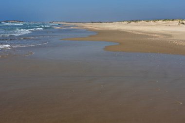 Hoş bir hava gününde Akdeniz kıyıları, ziyaretçileri güneşlenmeye ve denizin rahatlatıcı ritminin tadını çıkarmaya çağıran kumlu bir kıyıya sahiptir..