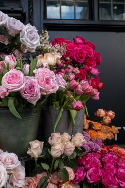 Bir buket pembe ranunculus ve kırmızı gül. Dükkanın girişinin dekorasyonu.