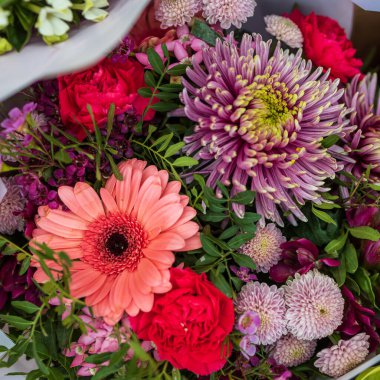 Pembe, kırmızı ve turuncu kasımpatılar ve kırmızı tonlarda yeşil okaliptüslü gerberalar.