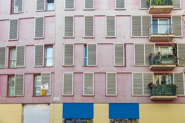 Pencereleri 70 'lerin tarzında, pembe panelleri ve balkonları olan yapıcı bir evin cephesi.