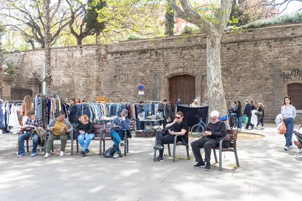 Barselona, İspanya - 26 Nisan 2023, Cumartesi öğleden sonraları insanlar bit pazarındaki banklarda otururlar. Kitap oku. Konuşuyorlar..