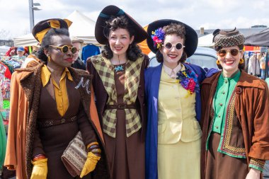 London UK - 15 Nisan 2023: Vintage 'dan Car Boot Sale. Retro festivali. İnsanlar klasik giysiler, mücevherler, klasik araçlarında ev eşyaları satıyorlar. Rockabilly tarzı giyinmiş kızlar