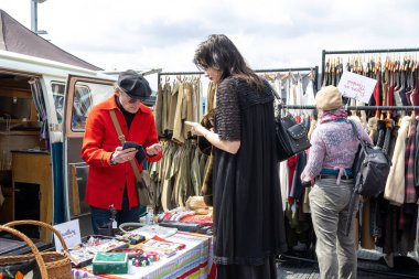 London UK - 15 Nisan 2023: Vintage 'dan Car Boot Sale. Retro festivali. İnsanlar klasik giysiler, mücevherler, klasik araçlarında ev eşyaları satıyorlar. Rockabilly tarzı giyinmiş kızlar