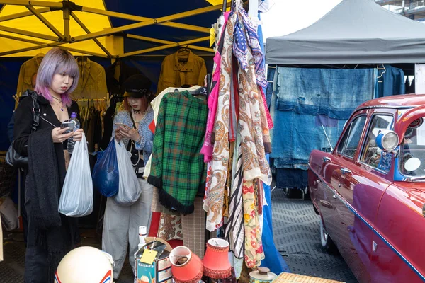 伦敦英国 2023年4月15日 以复古方式销售汽车 复古节人们在他们的经典汽车上出售老式服装 商品珠宝 家居用品 两个日本女孩选择衣服 — 图库照片