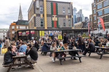 Londra, İngiltere - 12 Nisan 2023: Doğu Londralı bir kalabalık barın dışında bira içiyor..