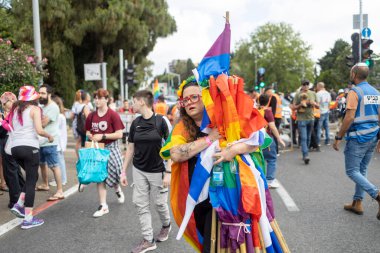 Hayfa, İsrail - 24 Haziran 2023: Geleneksel LGBTQ onur yürüyüşü için protesto tabelaları taşıyan insanlar. Gökkuşağı bayrakları taşıyan kadın