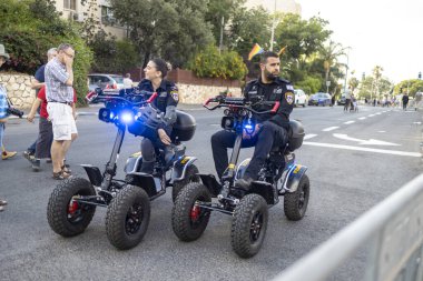 Hayfa, İsrail - 24 Haziran 2023: Geleneksel LGBTQ onur yürüyüşü için protesto tabelaları taşıyan insanlar. Polisler sokaklarda devriye geziyor.