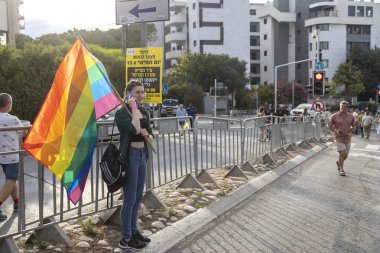 Hayfa, İsrail - 24 Haziran 2023: Geleneksel LGBTQ onur yürüyüşü için protesto tabelaları taşıyan insanlar. Gökkuşağı bayrağı sallayan kız