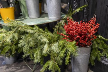 Çiçekçinin yanında çeşitli renkler var. Teneke vazolarda büyük buketler.
