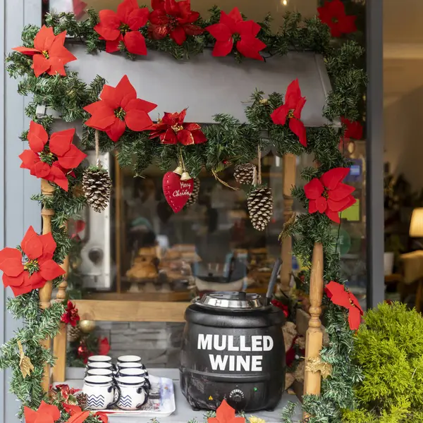 Table for selling mulled wine, decoration in the form of a poinsettia garland, cups for mulled wine. Christmas atmosphere in the cafe. Thermopot.