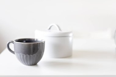 Beyaz masada iki porselen gri bardak var..